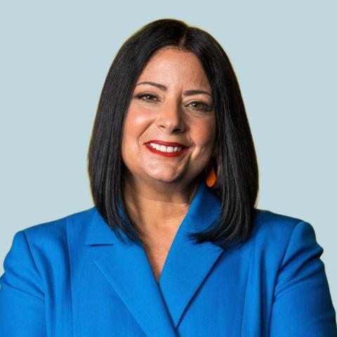 Image of woman with shoulder length dark hair wearing a bright blue suit jacket