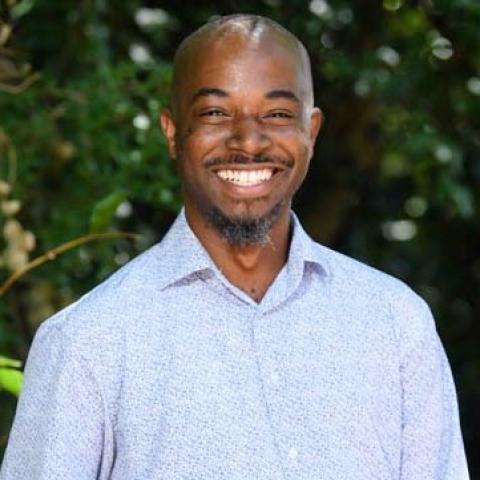 Outdoor image of smiling African American man wearing a blue shirt 