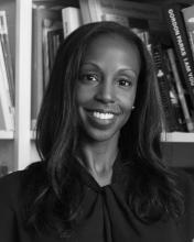 Black and white image of smiling African American woman  in front of a book shelf