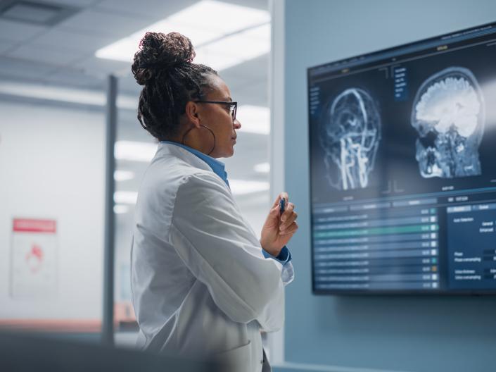 Side view of a  Black Female Neuroscientist inspecting a display of brain scans