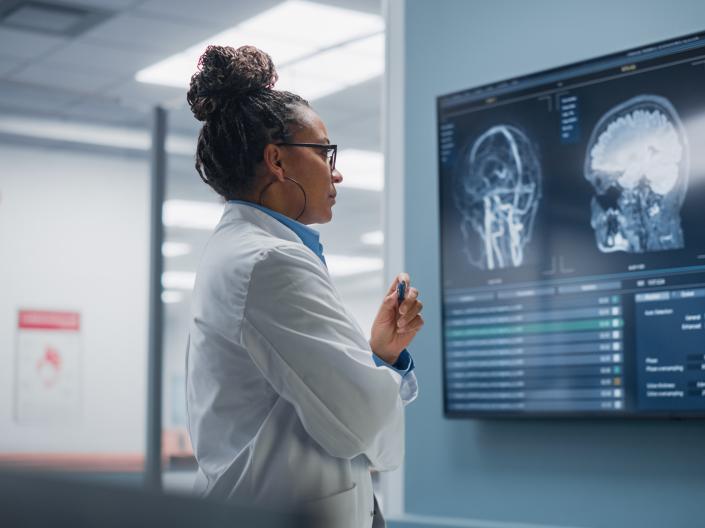 Side view of a Black Female Neuroscientist inspecting a display of brain scans