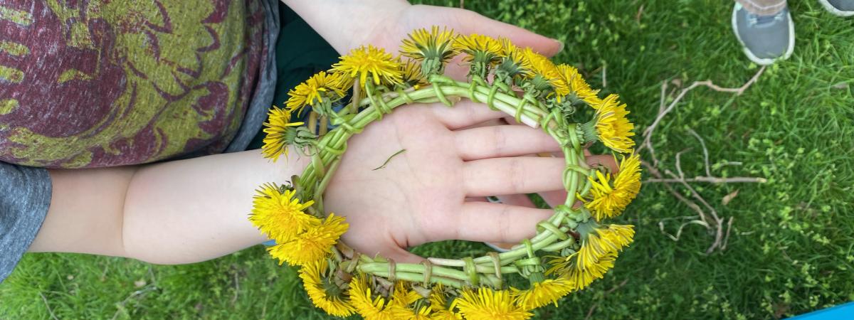 Hand holding dandelion crown