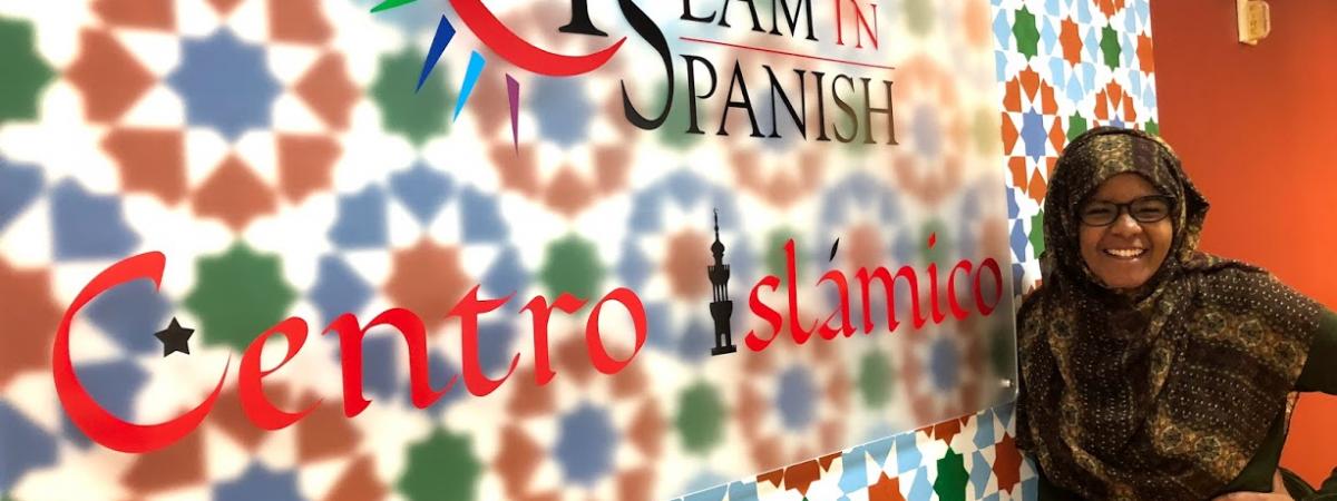 Female student poses next to an Islam in Spanish sign 