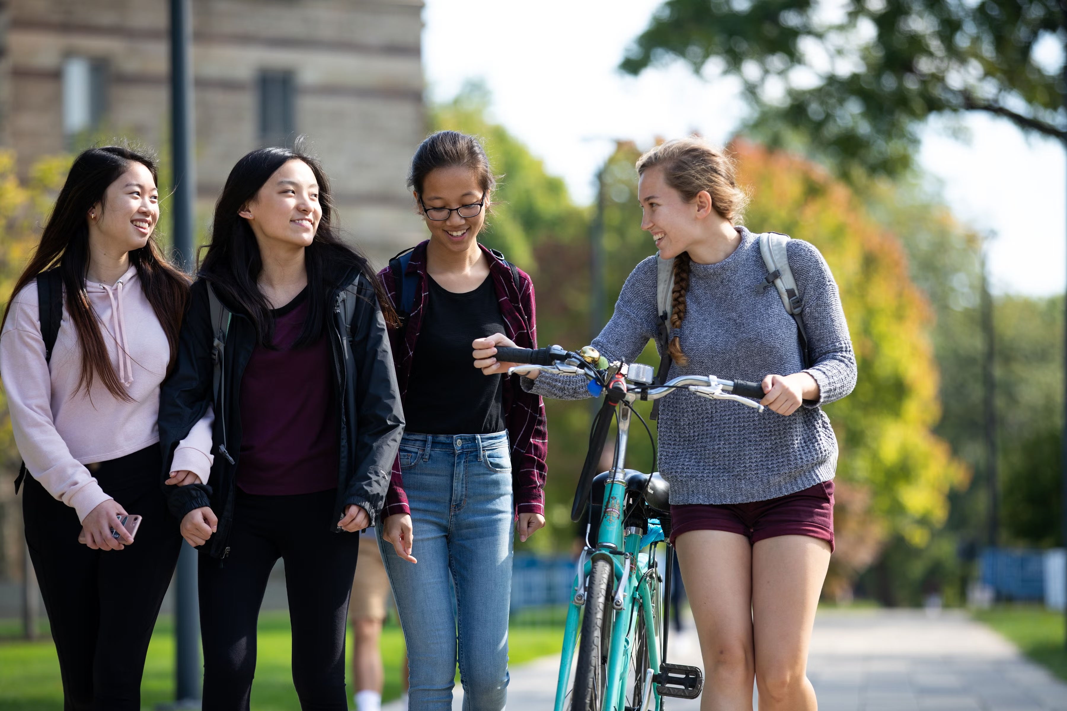 CWRU Female student walking on campus with bike.