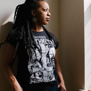 Laina Dawes wearing a black, heavy metal t-shirt and she's gazing out a window