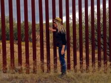 Sabine Feisst (Arizona State) next to fencing at border wall 