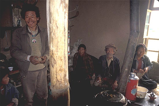 Photo of a Smiling man and three elderly individuals Inside a Tibetan household 