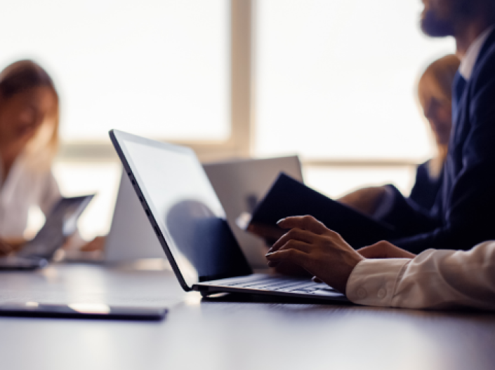 The image features a pair of office staff members' conversions, while one staff member is engaging with a laptop.