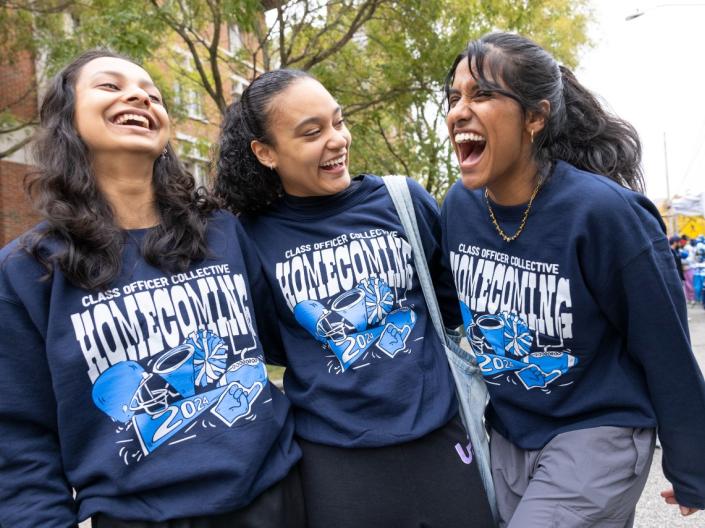 Students laughing together while wearing 2024 Homecoming sweaters