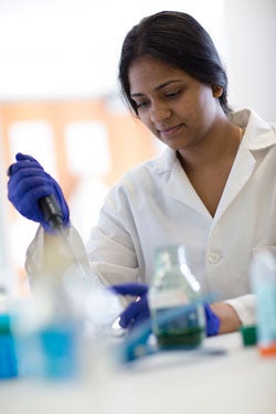 Photo of a femme scientist of color using lab equipment