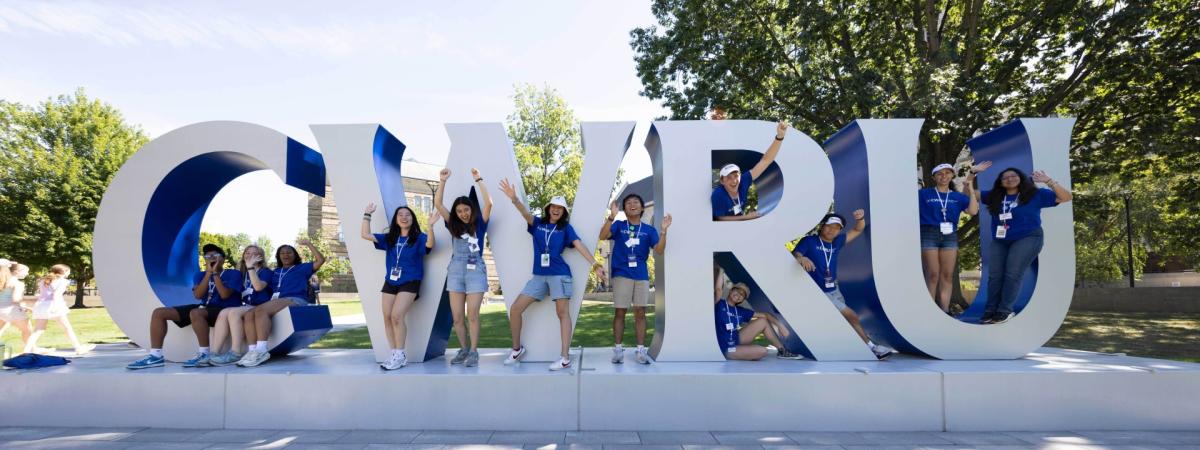 Students in CWRU shirts pose with the CWRU letters by Adelbert Hall.