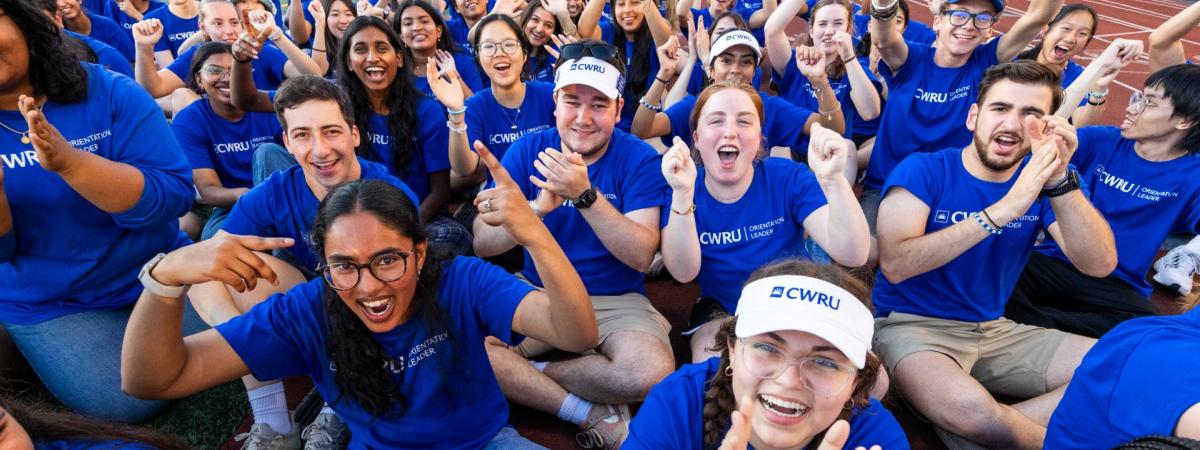 Students wearing blue CWRU shirts sit on the track clapping and cheering during Discover Week 2025.