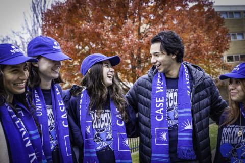 A group of students in CWRU apparel smile together for a photo at Homecoming.