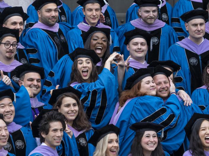A class of graduating Dental students smile and pose for a photo in their regalia.