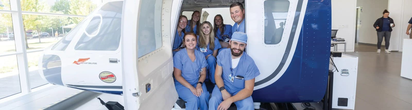 Medical professionals in scrubs beside clinical training equipment