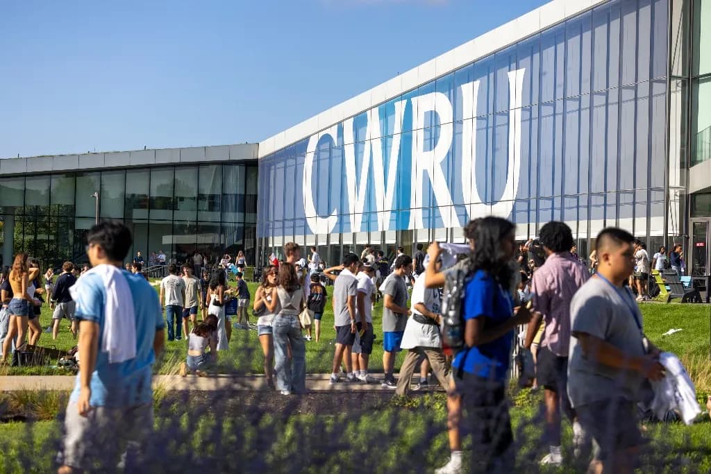 Students gathered on the lawn in front of a glass Case Western Reserve University building with CWRU lettering on the facade