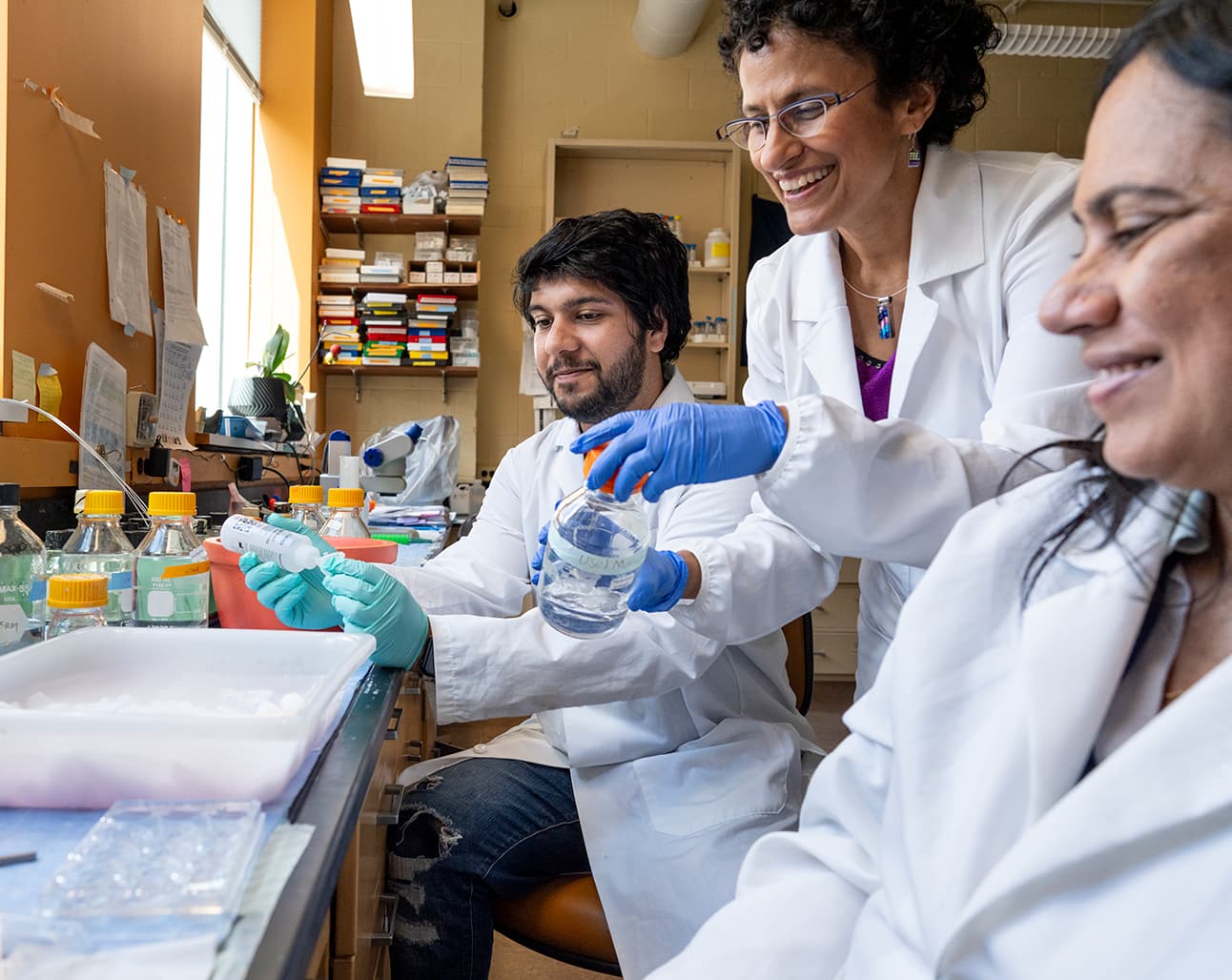 Researchers in a laboratory examining a glass bottle of liquid together