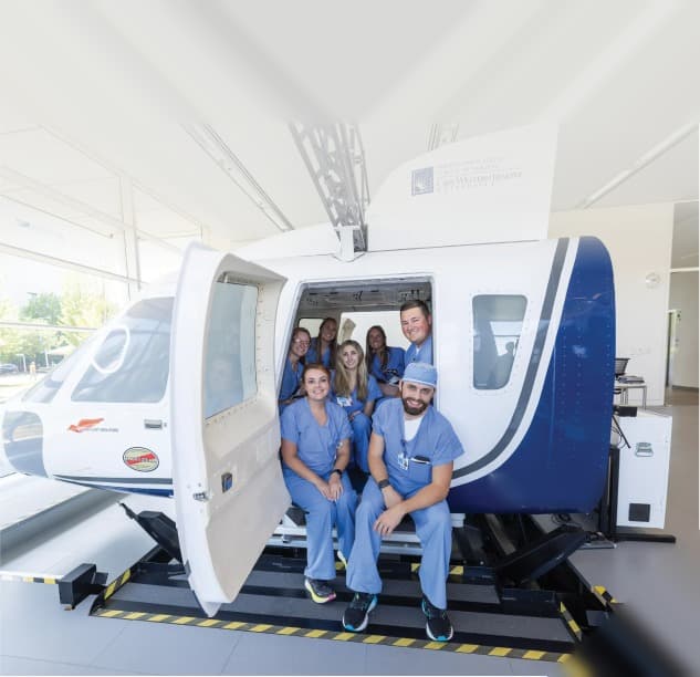 Medical professionals in scrubs beside clinical training equipment