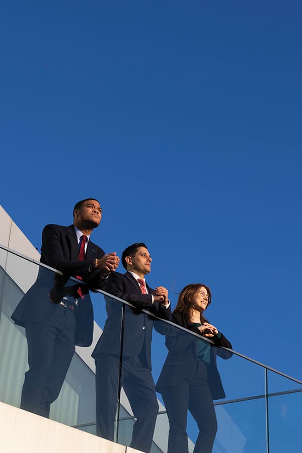 School of Law students overlooking from balcony in front of blue sky