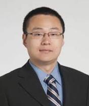 Headshot of Ming Hu. Man wearing glasses in a dark suit, blue dress shirt and striped tie.