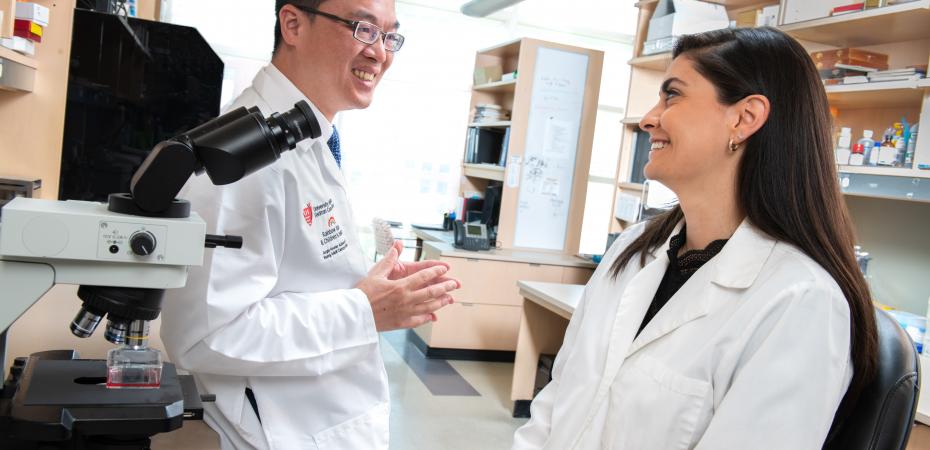 A mentor and mentee talking in the lab near a microscope
