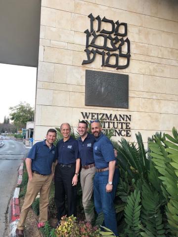Peter Scacheri, Stan Gerson, Mikkael Sekeres and Justin Lathia standing together, smiling in front of the Weizmann Insitute