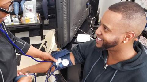 Man receiving blood pressure screening in barbershop