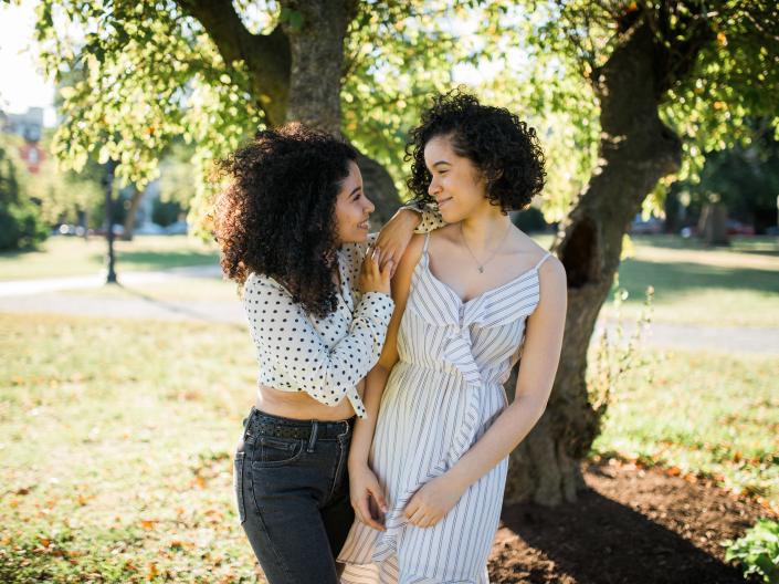 Photo of 2 sisters standing by a tree