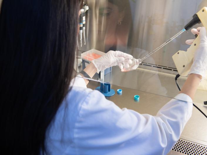 Woman at vent hood pipetting