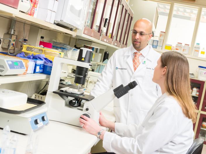 Mentor and mentee in lab in front of microscope