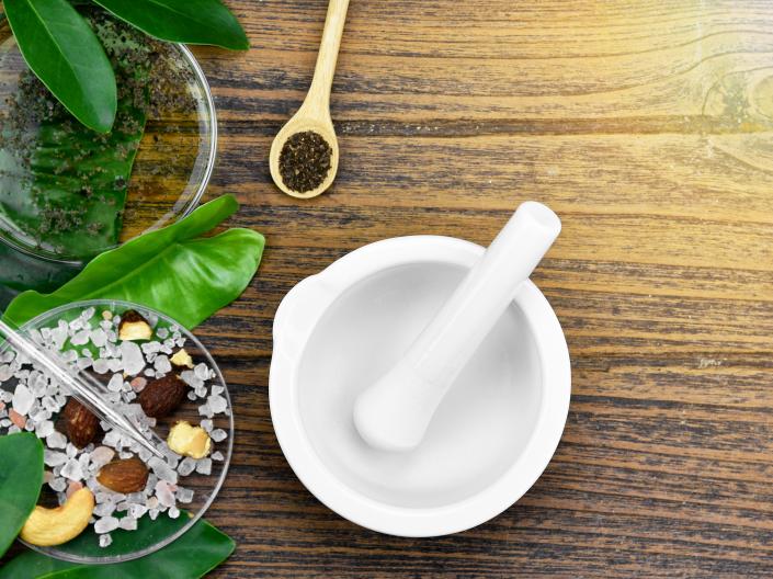 Image of mortar and pestle on wood table with leaves