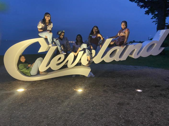 Six CanSUR students sitting on the Cleveland sign
