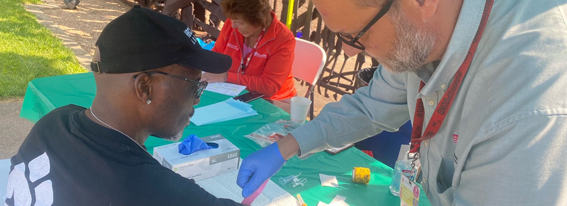A healthcare worker provides a screening at an outdoor community health event.