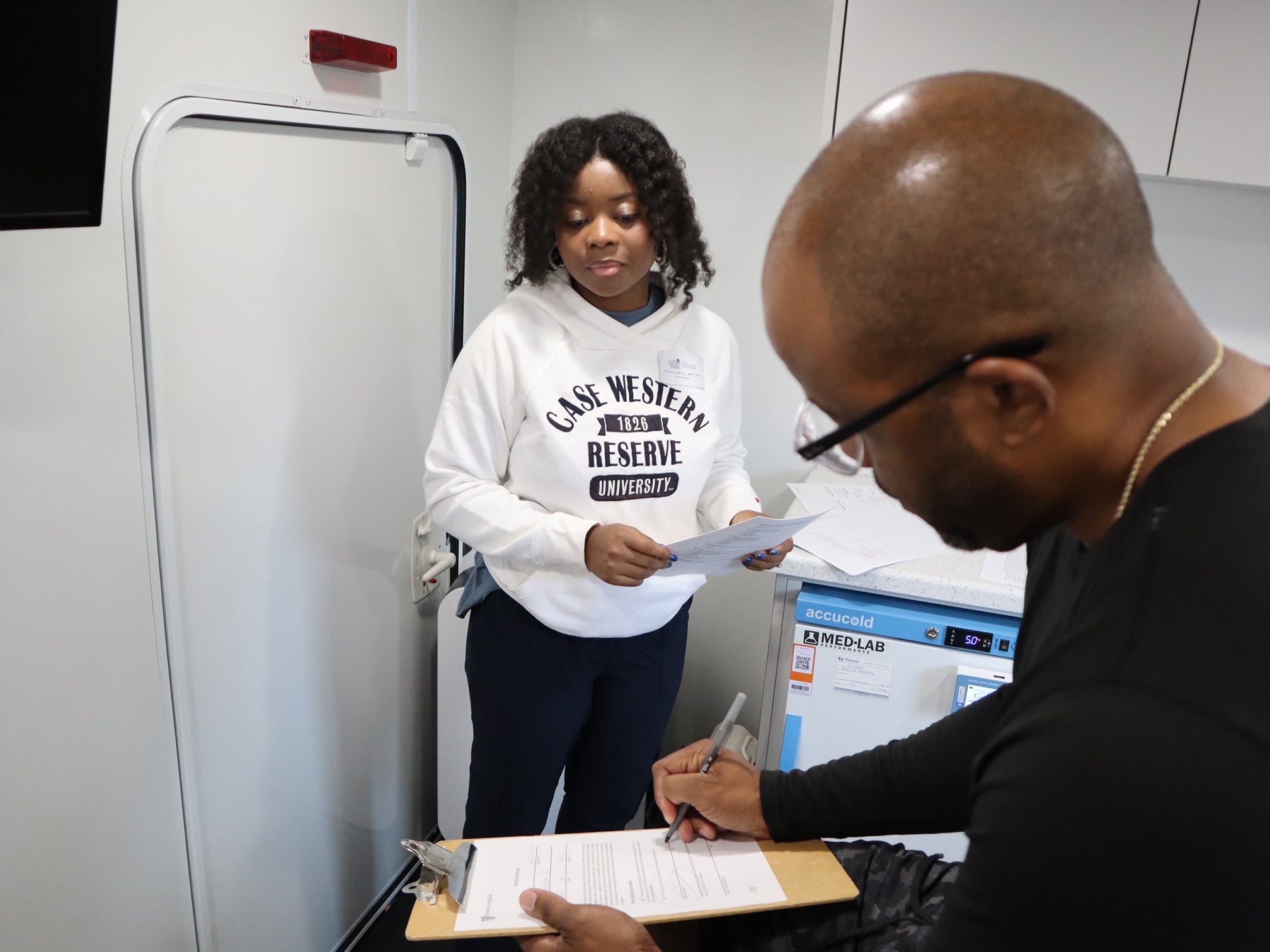 A clinical research participant completes consent paperwork with assistance from a research staff member before a study visit.
