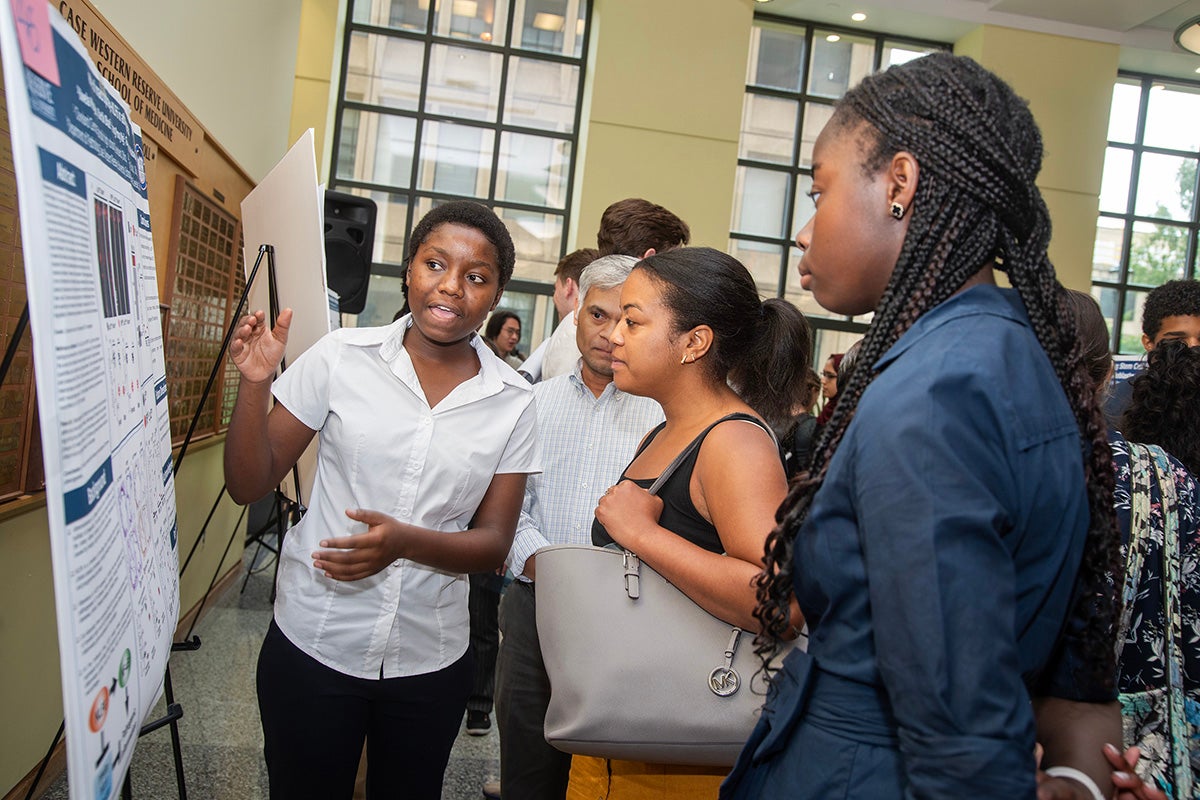 Student presents a research poster to attendees during an academic poster session at Case Western Reserve University.