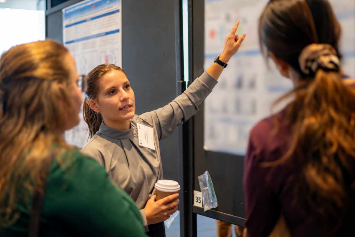 A researcher discusses her scientific poster with two attendees during the Case Comprehensive Cancer Center Annual Scientific Retreat.