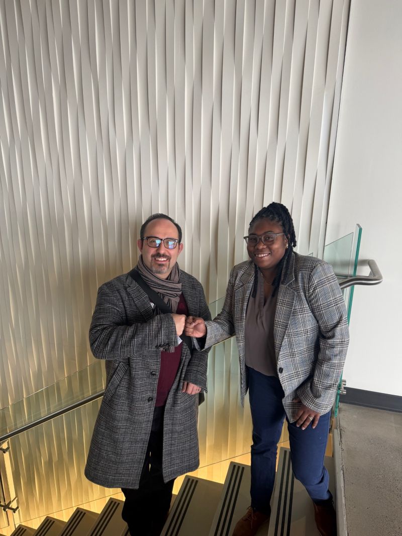 Murat Yildirim, PhD, and graduate student Tenesha Connor smile and fist-bump while standing together on a staircase.