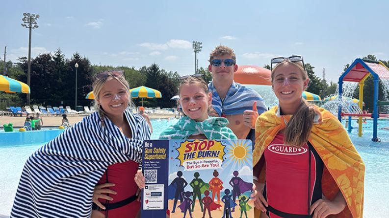 people in front of a pool holding a sunscreen card