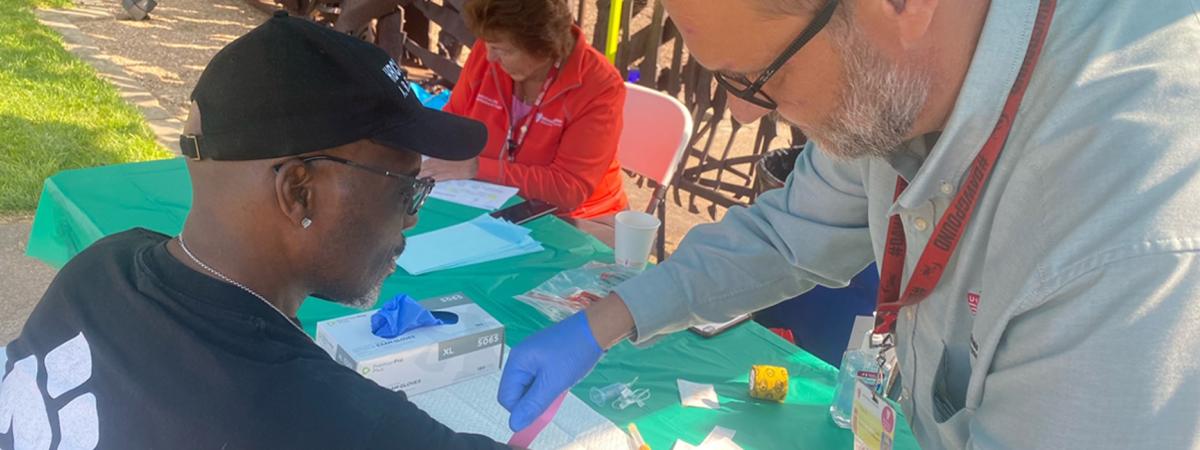 A healthcare worker provides a screening at an outdoor community health event.