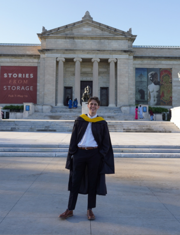 Photo of Jack Kincaid, in academic regalia, standing in front of Severance Hall, smiling