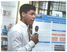 Connor Harris speaking into a microphone in front of a research poster