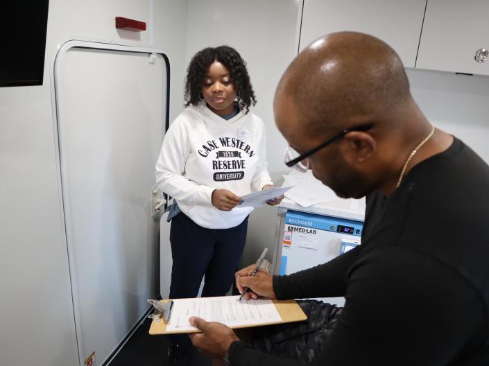 Individual completes paperwork with assistance from a staff member in a clinical setting.