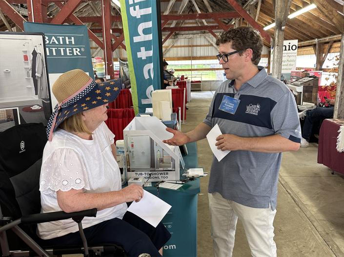 Case Comprehensive Cancer Center representative speaks with a community member at an outreach booth during a community health fair.