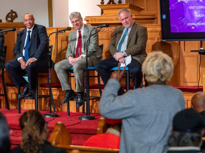 Community member asks a question during a health and wellness panel discussion as three speakers sit on stage with microphones inside a church sanctuary.