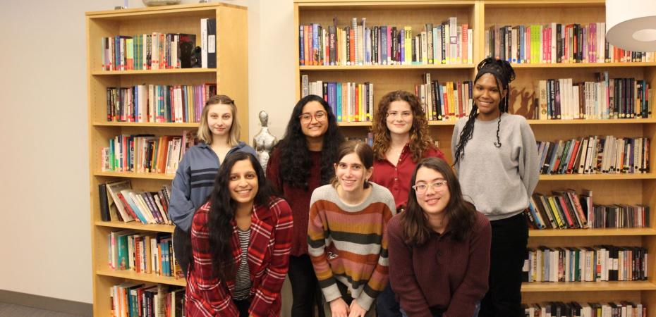 group of women standing in front of a bookcase