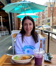young women sitting at a table with a bowl and smoothie in front of her