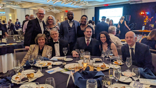 Group of 8 colleagues behind a round dinner party table dressed in evening attire for the The Kidney Foundation of Ohio 31st Annual Gala