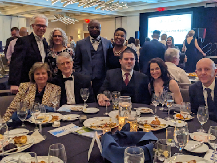 Group of 8 colleagues behind a round dinner party table dressed in evening attire for the The Kidney Foundation of Ohio 31st Annual Gala