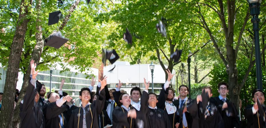 gradutes tossing graduation hats