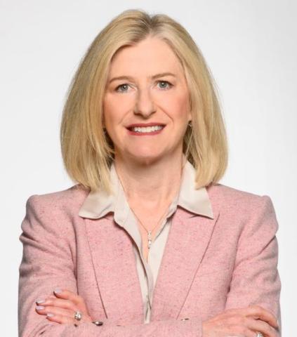 Woman in pink blazer with arms crossed.